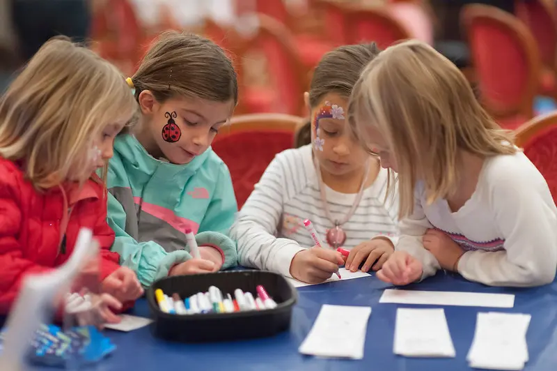 テーブルを囲んで絵を描く、フェイスペイントをした4人の子どもたち